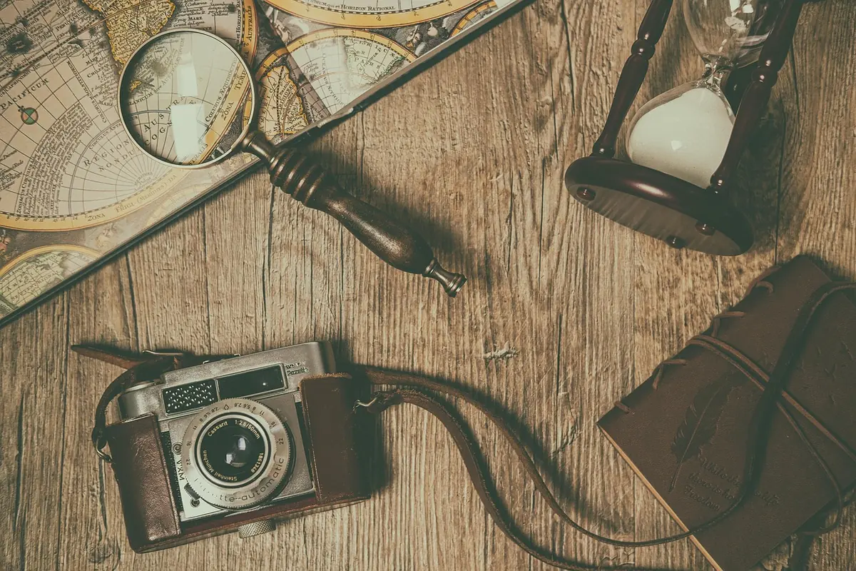 A desk with a magnifying glass, camera and notebook
