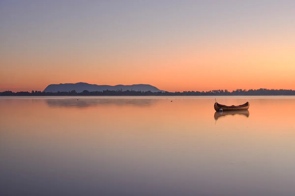 A small boat on a calm lake at sunset
