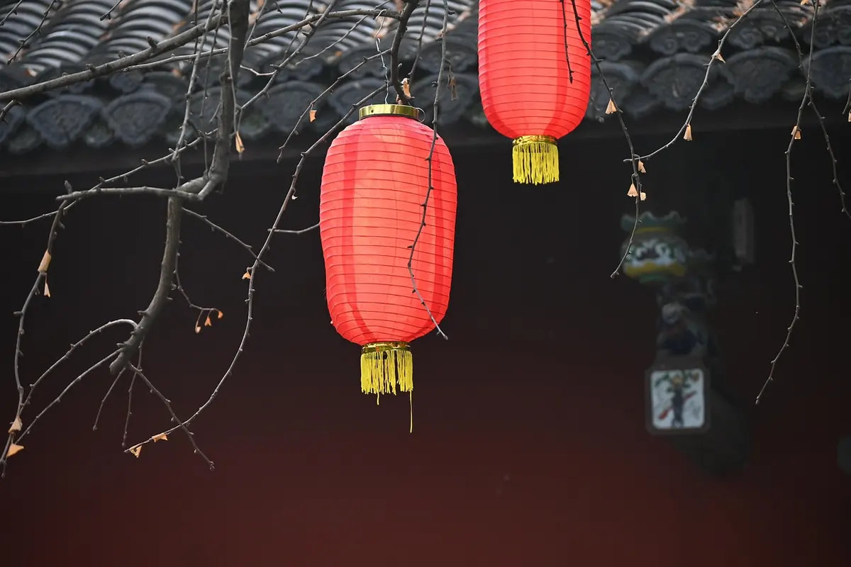 Red paper lanterns hanging from a temple roof
